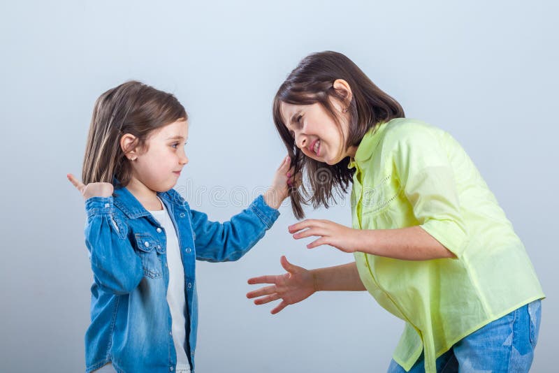 Le conflit entre les soeurs, une plus jeune soeur tire les cheveux un SI plus ancien photos stock Le conflit entre les soeurs, une plus jeune soeur tire les cheveux un SI plus ancien photos stock