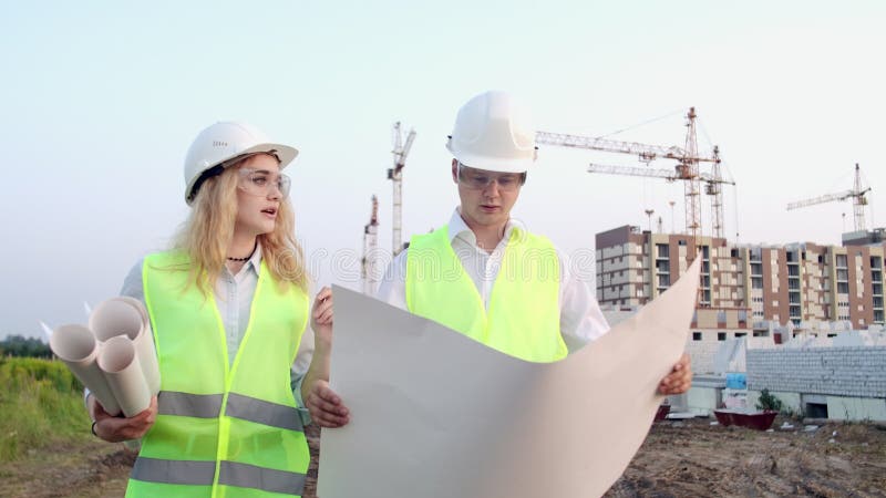 Le constructeur et architecte homme et femme discutent du plan de construction du centre d'affaires moderne situÃ© Ã  proximitÃ©