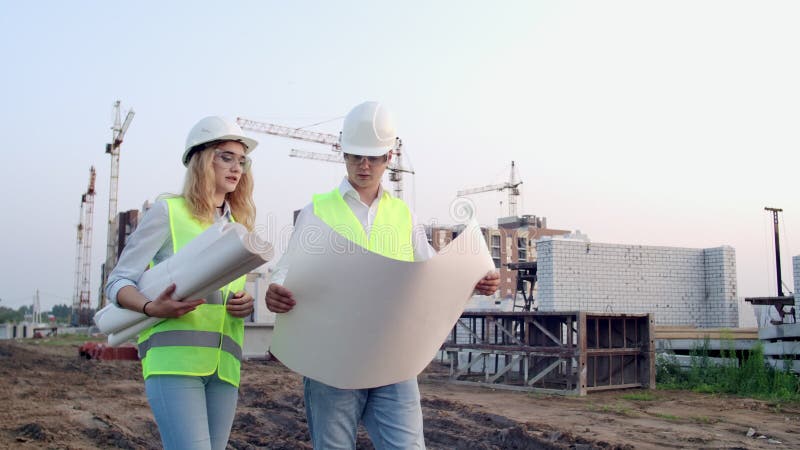 Le constructeur et architecte homme et femme discutent du plan de construction du centre d'affaires moderne situÃ© Ã  proximitÃ©