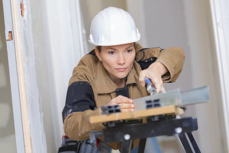 Le constructeur féminin utilisant la table électronique de machine a vu la coupe image libre de droits Le constructeur féminin utilisant la table électronique de machine a vu la coupe image libre de droits