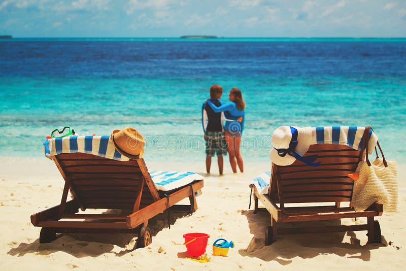 Le coppie felici si rilassano sulla spiaggia tropicale fotografia stock Le coppie felici si rilassano sulla spiaggia tropicale fotografia stock