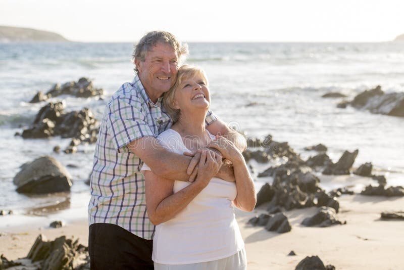 Le coppie mature senior adorabili sul loro 60s o 70s si sono ritirate la camminata felice e rilassata sulla riva di mare della sp