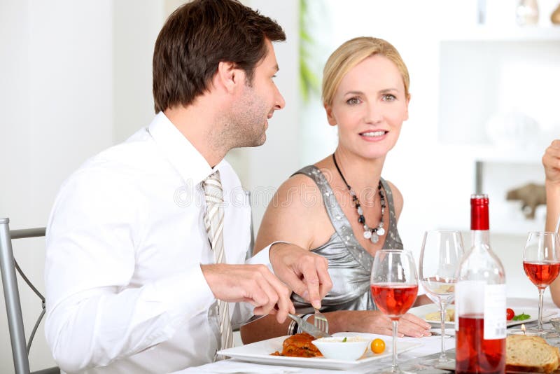 Le coppie si sono sedute alla tabella che mangia il pasto fotografia stock Le coppie si sono sedute alla tabella che mangia il pasto fotografia stock