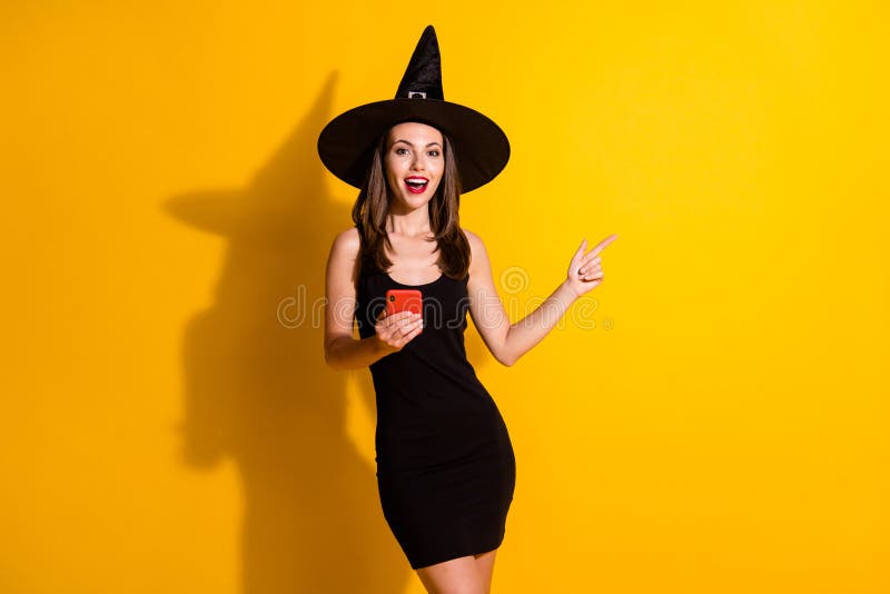 Photo excited spooky witch lady use smartphone point index finger, copyspace mysterious boo enchant adverts wear black cap headwear skirt isolated bright shine color background. Photo excited spooky witch lady use smartphone point index finger, copyspace mysterious boo enchant adverts wear black cap headwear skirt isolated bright shine color background