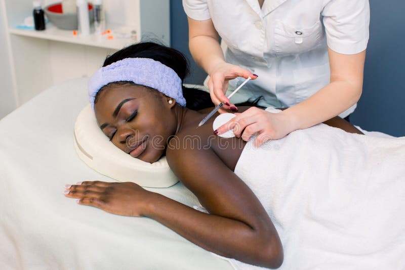 Le cosmetologist de docteur de jeune femme injecte la solution mesotherapy ou sp?ciale au dos de la jolie femme africaine dans la images stock Le cosmetologist de docteur de jeune femme injecte la solution mesotherapy ou sp?ciale au dos de la jolie femme africaine dans la images stock