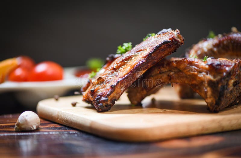 Le costole di carne di maiale del Bbq grigliate con il ketchup di pomodori e le spezie delle erbe sono servito sulla tavola - cos fotografia stock Le costole di carne di maiale del Bbq grigliate con il ketchup di pomodori e le spezie delle erbe sono servito sulla tavola - cos fotografia stock
