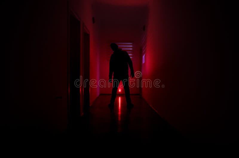 Le couloir sombre avec des portes de coffret et les lumières avec la silhouette de l'horreur fantasmagorique équipent la position photographie stock Le couloir sombre avec des portes de coffret et les lumières avec la silhouette de l'horreur fantasmagorique équipent la position photographie stock