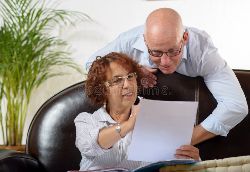 Le couple supérieur regarde un document image stock Le couple supérieur regarde un document image stock