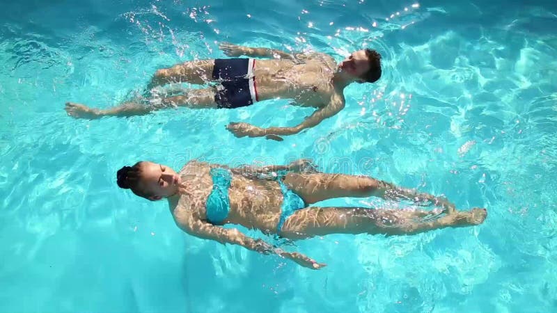 Le couple a un repos dans la piscine avec le champagne ils sourient, étreignent et embrassent