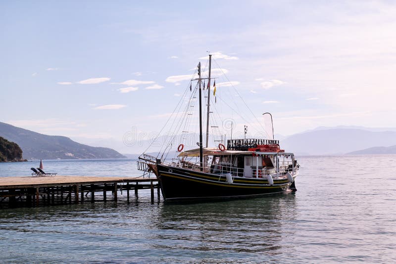 Le croiseur de bateau de touristes dans la petite marina sur la mer et la belle plage, les touristes de attente pour le bateau na photo stock Le croiseur de bateau de touristes dans la petite marina sur la mer et la belle plage, les touristes de attente pour le bateau na photo stock
