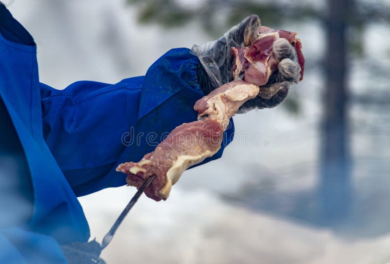 Le cuisinier en plein air, dans la rue met la viande sur une brochette photos stock Le cuisinier en plein air, dans la rue met la viande sur une brochette photos stock