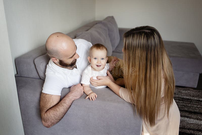 Le den deras modern och fadern som rymmer, behandla som ett barn flickadottern som hemma sitter på säng Lyckligt familjbegrepp, s royaltyfri foto Le den deras modern och fadern som rymmer, behandla som ett barn flickadottern som hemma sitter på säng Lyckligt familjbegrepp, s royaltyfri foto
