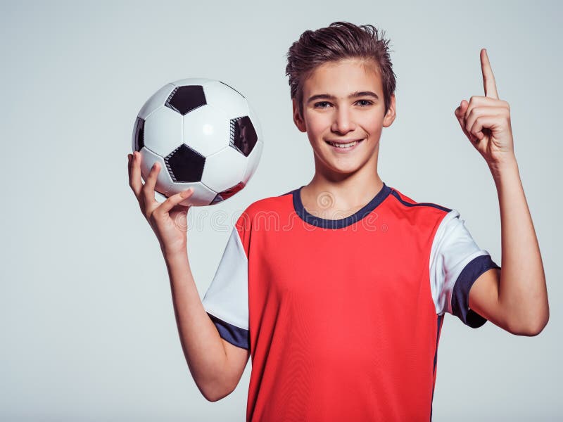 Le den tonåriga pojken i hållande fotbollboll för sportswear arkivfoton Le den tonåriga pojken i hållande fotbollboll för sportswear arkivfoton