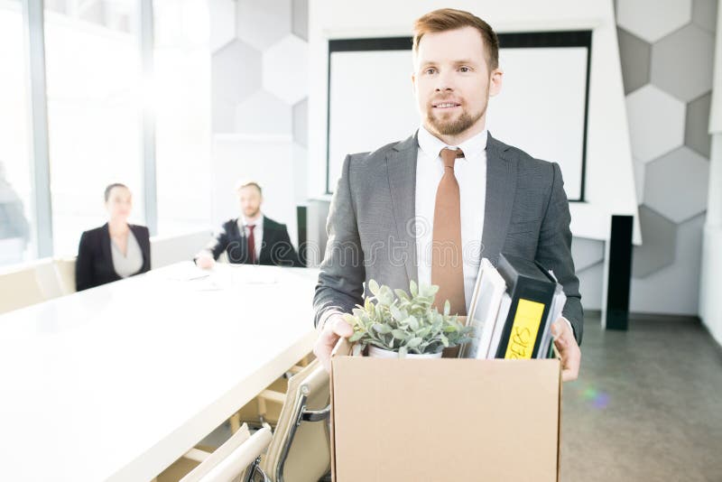Waist up portrait of handsome bearded businessman holding box of personal belongings and leaving office after being fired from job, copy space. Waist up portrait of handsome bearded businessman holding box of personal belongings and leaving office after being fired from job, copy space