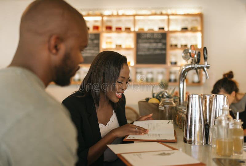 Le den unga afrikanska amerikanen koppla ihop läs- menyer i en stång arkivfoton Le den unga afrikanska amerikanen koppla ihop läs- menyer i en stång arkivfoton