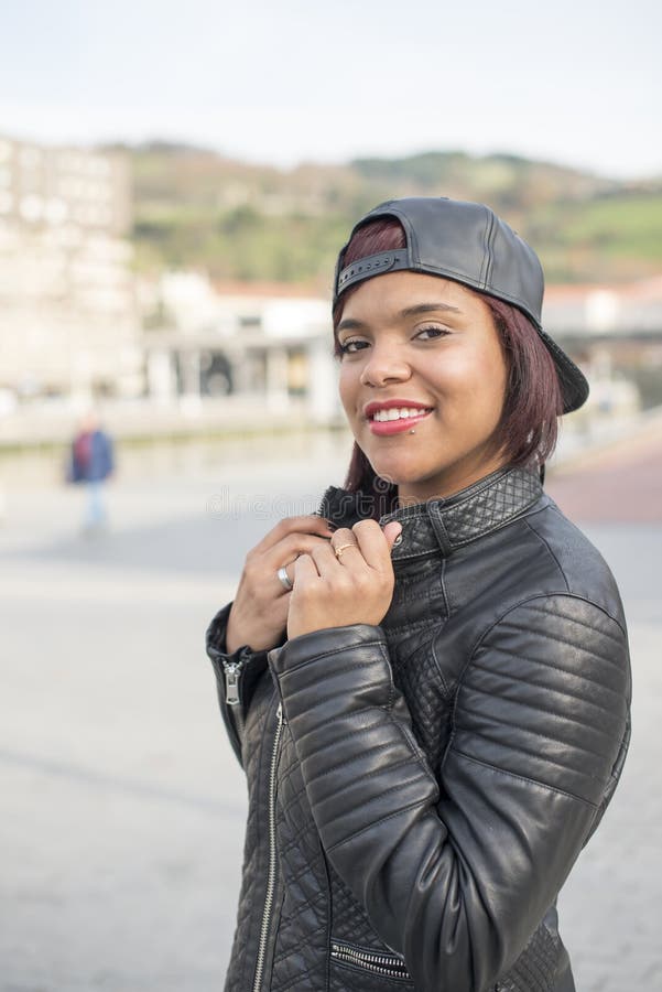 Le den unga latinska kvinnan med baseballmössan i gatan arkivfoton Le den unga latinska kvinnan med baseballmössan i gatan arkivfoton