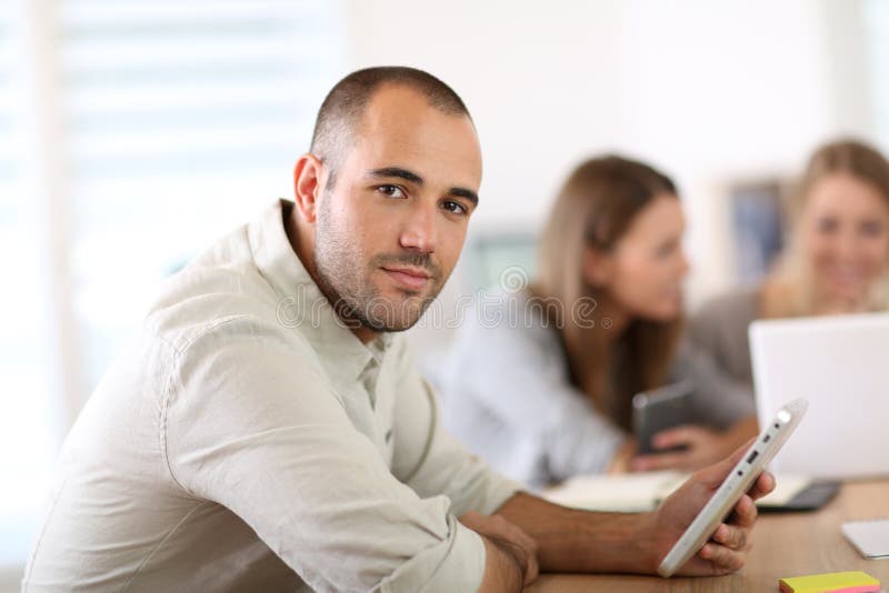 Le den unga mannen på kontoret med coworkers beside arkivfoton Le den unga mannen på kontoret med coworkers beside arkivfoton