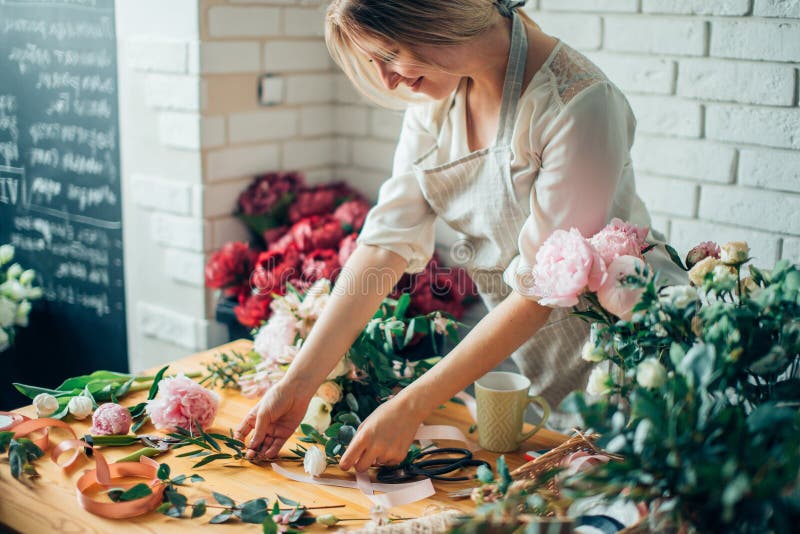 Le den älskvärda blomsterhandlaren för ung kvinna som ordnar växter i blomsterhandel
