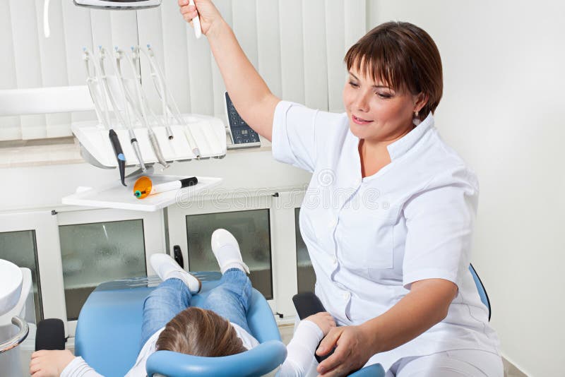 Le dentiste ajuste la lumière avant examen photographie stock libre de droits Le dentiste ajuste la lumière avant examen photographie stock libre de droits