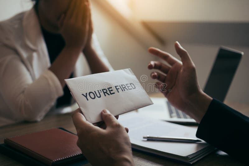 Le directeur mâle est parlant ou expliquant au sujet de devoir répandre l'employé-e tout en étant distribué une enveloppe de démis images libres de droits