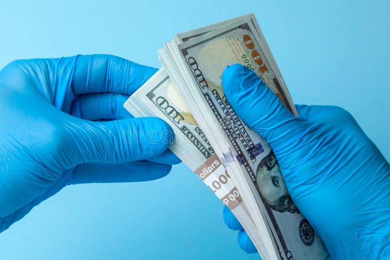 Le docteur dans les gants bleus tient des dollars d'argent liquide d'argent sur le fond bleu Concept de paiement illicite, de cor photos libres de droits Le docteur dans les gants bleus tient des dollars d'argent liquide d'argent sur le fond bleu Concept de paiement illicite, de cor photos libres de droits