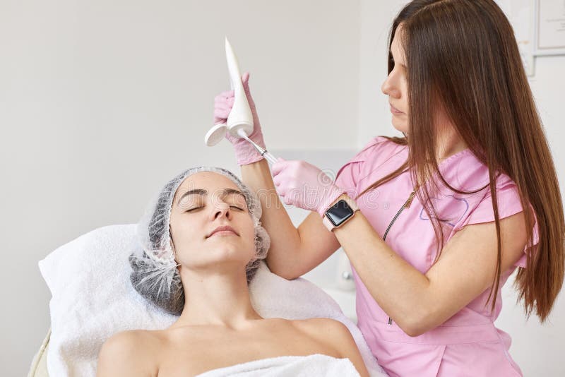 Le docteur serre l'agent cosmetological de la bouteille, se prépare à hydrater la procédure La femme au salon de beauté, détend s photos libres de droits Le docteur serre l'agent cosmetological de la bouteille, se prépare à hydrater la procédure La femme au salon de beauté, détend s photos libres de droits