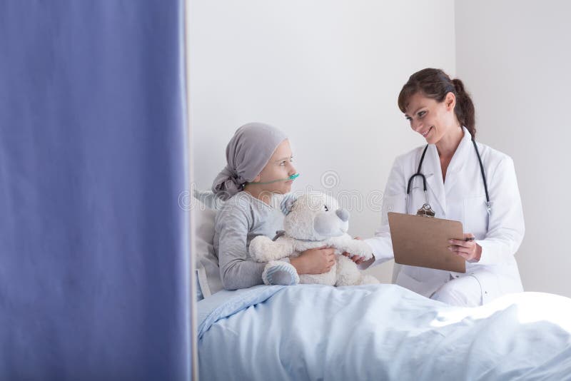 Le doktorn med stetoskopet som talar med ungen med cancer som kramar den flotta leksaken royaltyfria foton Le doktorn med stetoskopet som talar med ungen med cancer som kramar den flotta leksaken royaltyfria foton