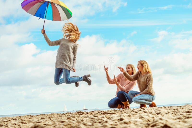 Le donne che saltano con l'ombrello immagine stock Le donne che saltano con l'ombrello immagine stock