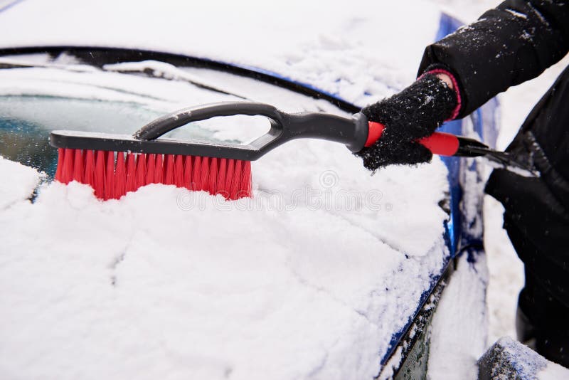 Women hand in black glove removes snow from car windshield. Women hand in black glove removes snow from car windshield