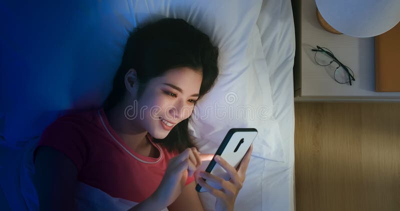 Le donne usano lo smartphone sul letto fotografie stock libere da diritti