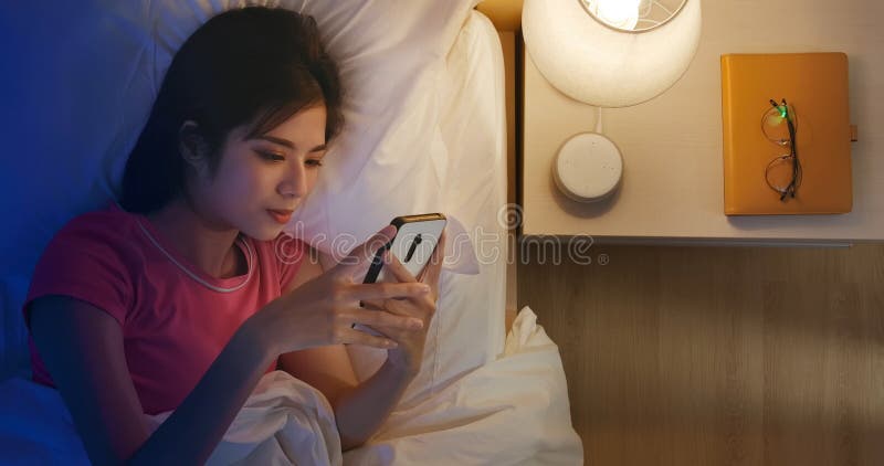 Le donne usano lo smartphone sul letto immagini stock libere da diritti