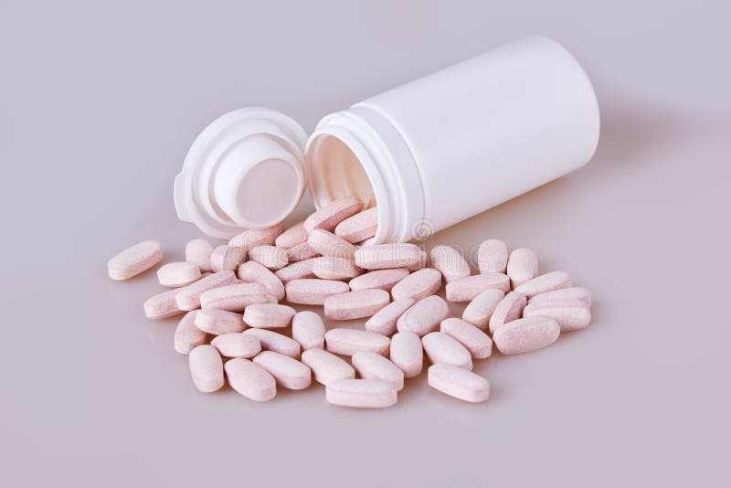 Le droghe delle vitamine hanno sparso e si rovesciate fuori vicino ad una bottiglia di plastica bianca aperta della medicina fotografia stock libera da diritti Le droghe delle vitamine hanno sparso e si rovesciate fuori vicino ad una bottiglia di plastica bianca aperta della medicina fotografia stock libera da diritti