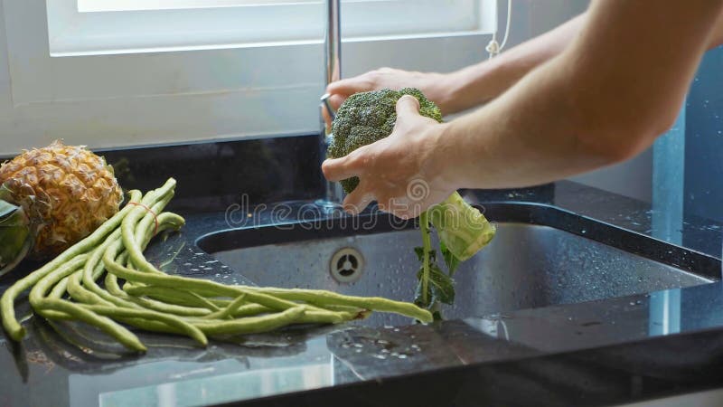 Le ` en gros plan s de femme remet le brocoli de lavage à la cuisine domestique image libre de droits Le ` en gros plan s de femme remet le brocoli de lavage à la cuisine domestique image libre de droits