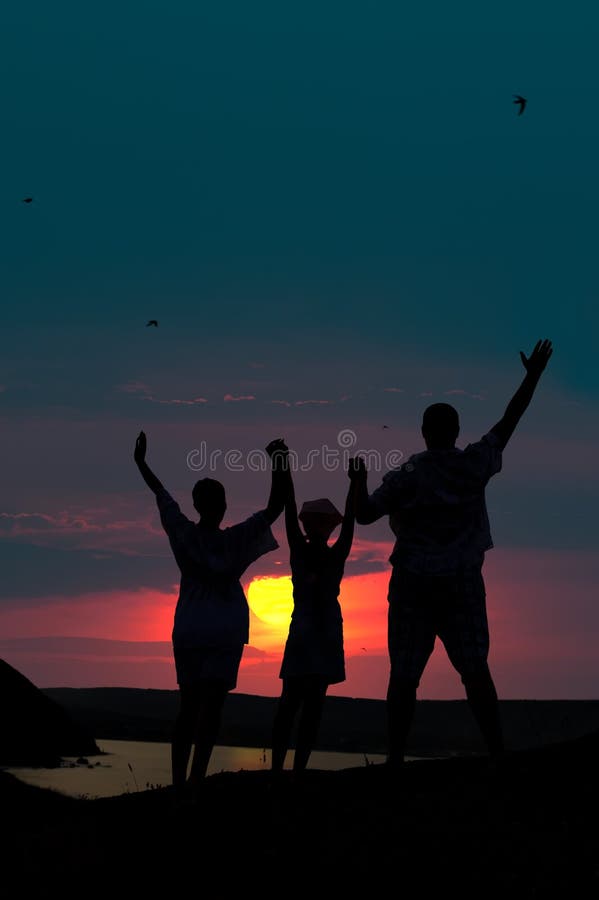 The family from three persons welcomes the sunset sun. The family from three persons welcomes the sunset sun.