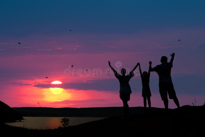 The family from three persons welcomes the sunset sun. The family from three persons welcomes the sunset sun.