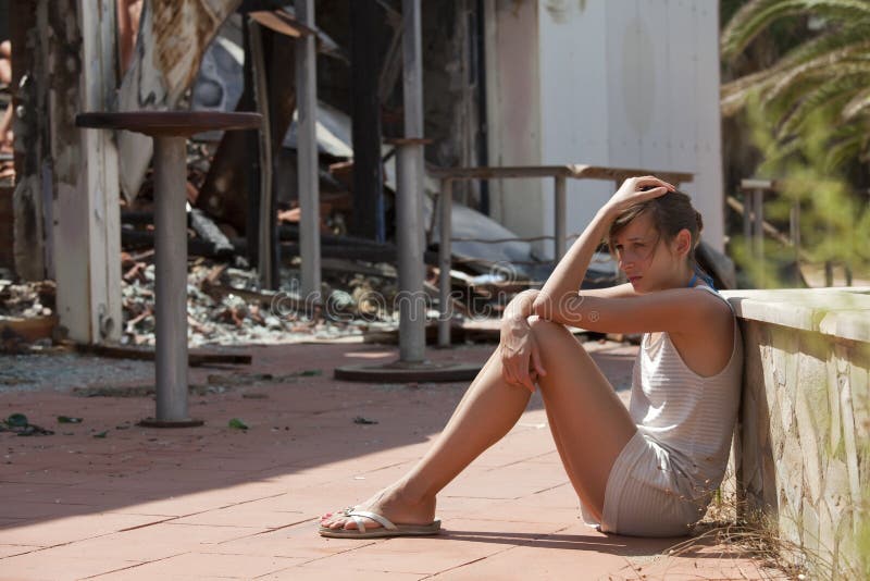 Sad woman sitting in front of burned out house. Sad woman sitting in front of burned out house