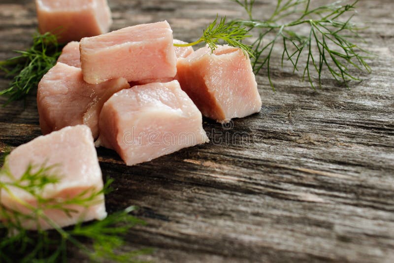 Le filet cru de poulet a coupé en cubes avec l'aneth vert sur une surface en bois image stock Le filet cru de poulet a coupé en cubes avec l'aneth vert sur une surface en bois image stock