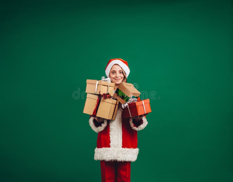 Le flickan i den Santa Claus klänningen som rymmer hennes julgåvor royaltyfri fotografi Le flickan i den Santa Claus klänningen som rymmer hennes julgåvor royaltyfri fotografi
