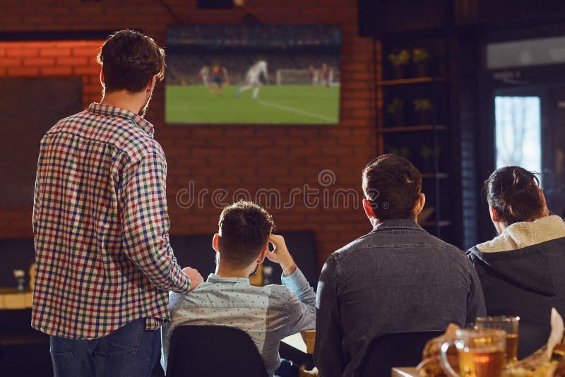 Le football de observation des jeunes à la TV dans la barre photo libre de droits Le football de observation des jeunes à la TV dans la barre photo libre de droits