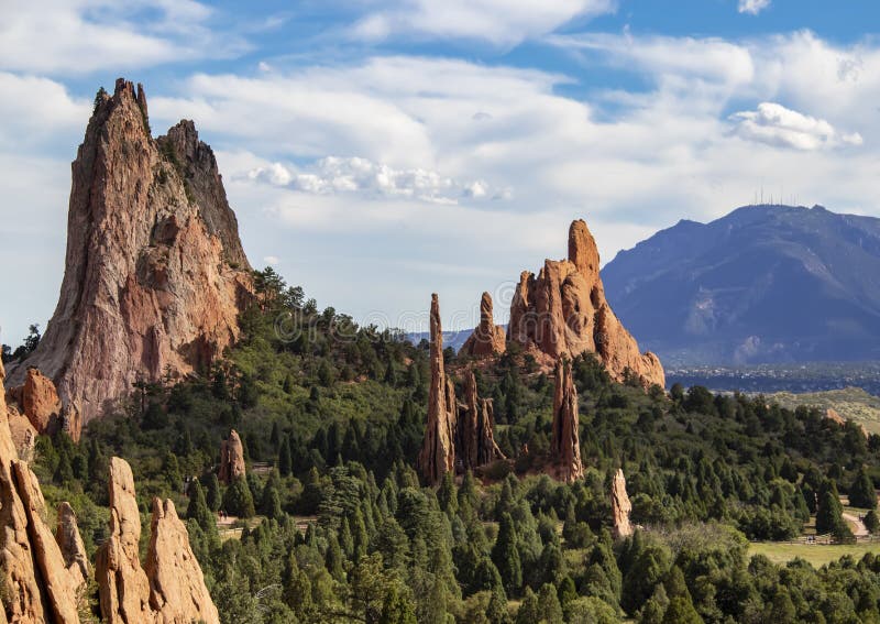 Le formazioni rocciose rosse torreggianti del giardino dei di Colorado Springs con Cheyenne Mountain nei precedenti immagini stock libere da diritti Le formazioni rocciose rosse torreggianti del giardino dei di Colorado Springs con Cheyenne Mountain nei precedenti immagini stock libere da diritti