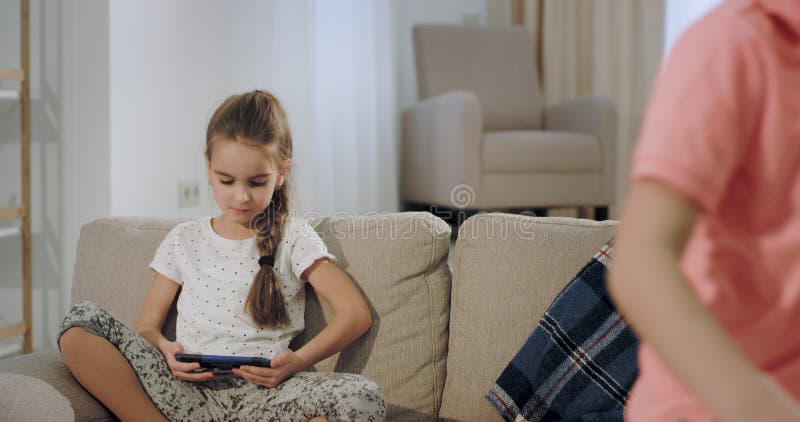 Le frère et la petite soeur ont un moment ensemble après école qu'ils prennent se reposent sur le sofa et prennent un smartpho