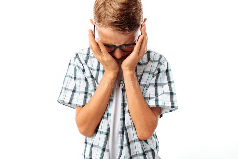 Le garçon de l'adolescence que le renversement essuie ses larmes de main, frustration après école, dans le studio sur un fond bla photo stock Le garçon de l'adolescence que le renversement essuie ses larmes de main, frustration après école, dans le studio sur un fond bla photo stock