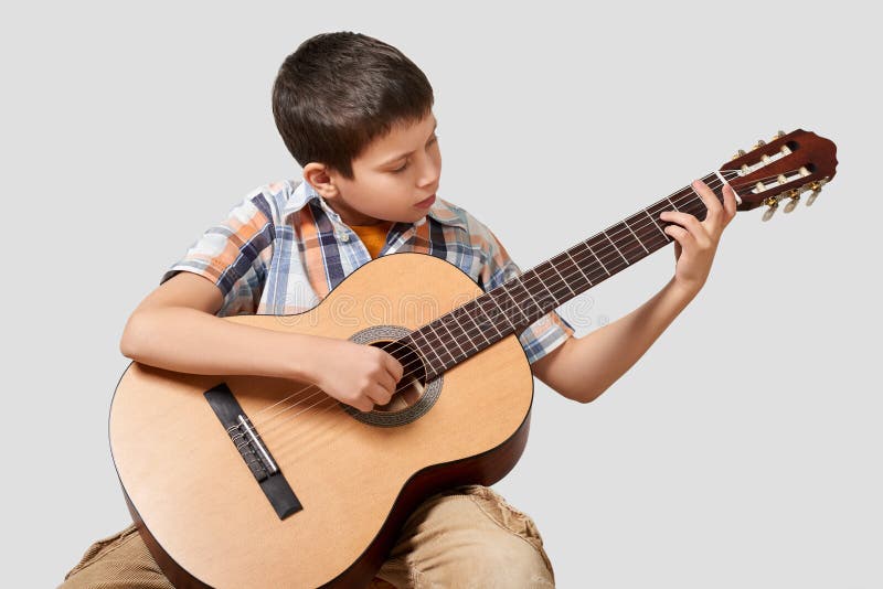 Le garçon joue la guitare acoustique image stock Le garçon joue la guitare acoustique image stock