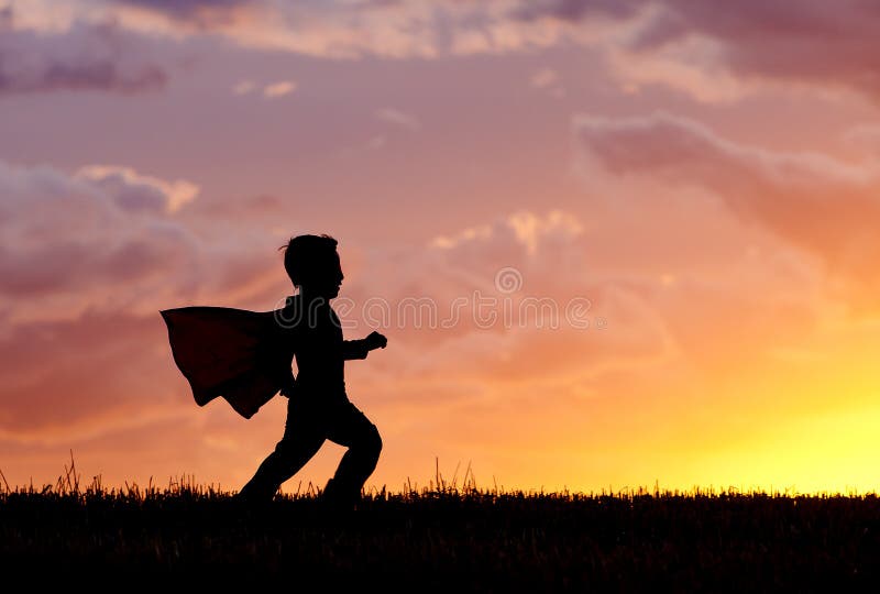 Le garçon joue le héros superbe au coucher du soleil. images stock Le garçon joue le héros superbe au coucher du soleil. images stock
