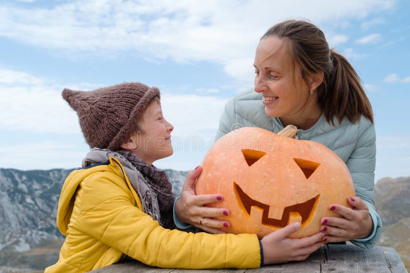 Le garçon mignon dans le chapeau avec la mère et le Halloween a découpé le potiron sur photographie stock Le garçon mignon dans le chapeau avec la mère et le Halloween a découpé le potiron sur photographie stock