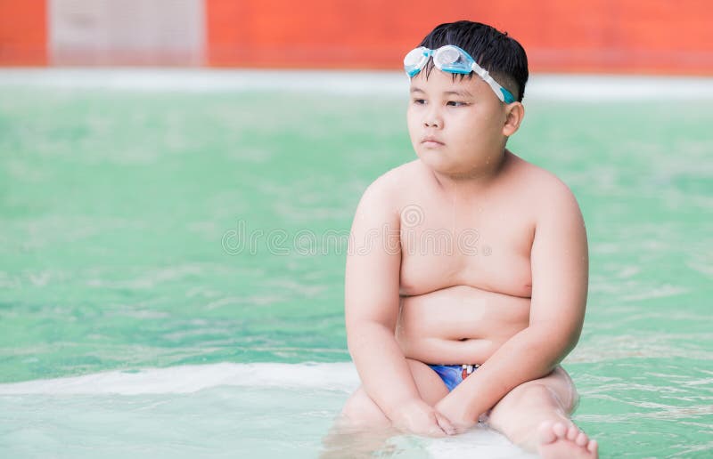 Le garçon obèse s'asseyent dans la piscine photo stock Le garçon obèse s'asseyent dans la piscine photo stock