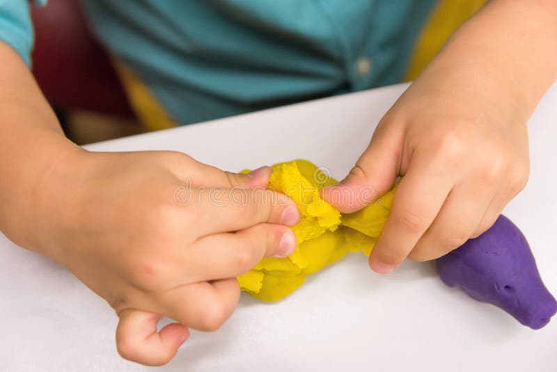 Le garçon quatre caucasien an fait avec les chiffres animaux de mains à partir de modeler l'argile jaune sur le dessus de table b photos stock Le garçon quatre caucasien an fait avec les chiffres animaux de mains à partir de modeler l'argile jaune sur le dessus de table b photos stock