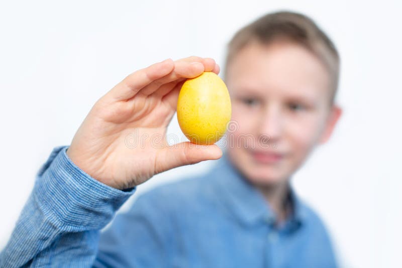 Le garçon tient les oeufs colorés Oeuf jaune dans les mains du garçon Le garçon gai tient des oeufs près des yeux Fond blanc photos libres de droits Le garçon tient les oeufs colorés Oeuf jaune dans les mains du garçon Le garçon gai tient des oeufs près des yeux Fond blanc photos libres de droits