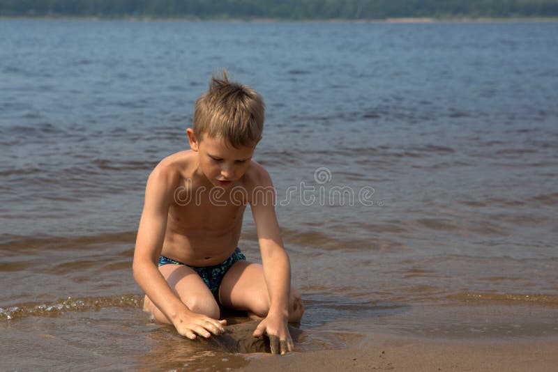 Le garçon établit des figures du sable sur la plage photographie stock libre de droits Le garçon établit des figures du sable sur la plage photographie stock libre de droits