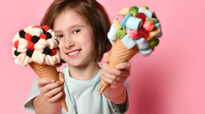 Le gentil enfant de l'adolescence de sourire de fille donne, offre ou nous montre deux grande crème glacée dans le cône de gaufre photos stock Le gentil enfant de l'adolescence de sourire de fille donne, offre ou nous montre deux grande crème glacée dans le cône de gaufre photos stock